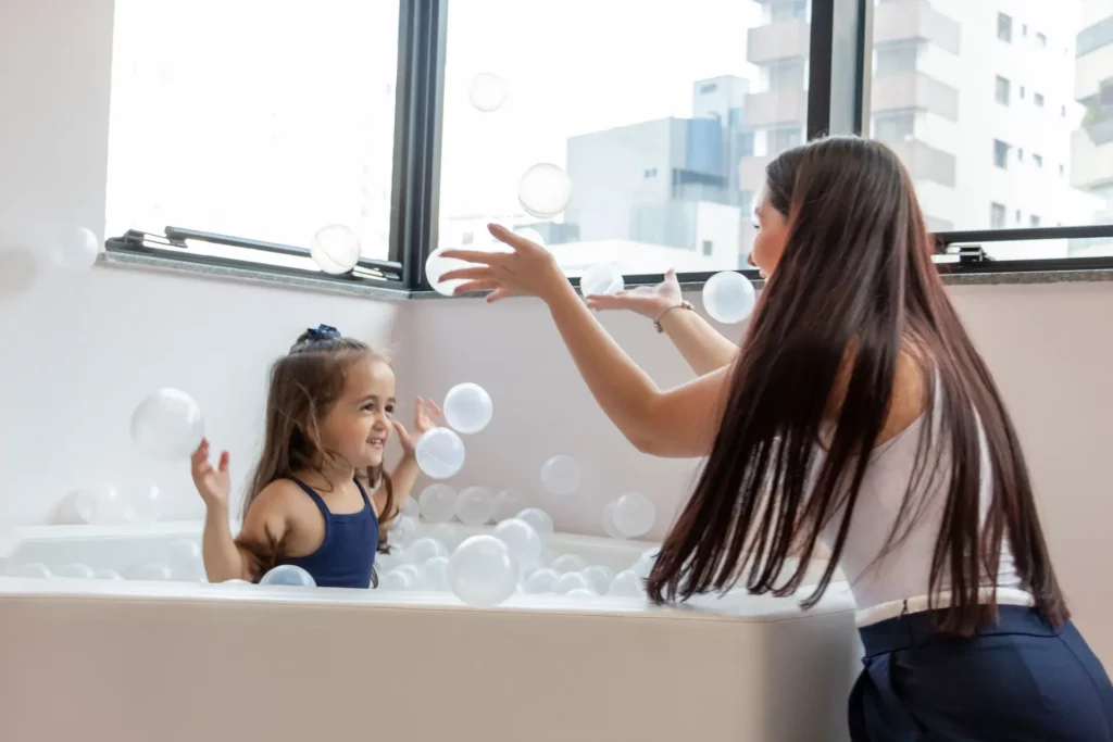 mulher brincando com uma criança dentro de uma banheira com bolinhas